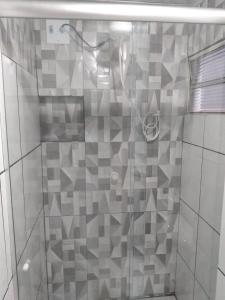 a shower with a glass door with gray tiles at HOTEL NOVAES in Castanhal
