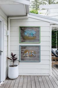 a white house with two framed paintings on a porch at The Patonga Cottage in Patonga