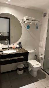 a bathroom with a toilet and a sink and a mirror at Flat Suites em Hotel de Luxo in Maceió