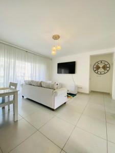 a living room with a white couch and a tv at Vista Golf II Playa Nueva Romana in San Pedro de Macorís