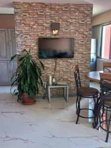 a living room with a brick wall with a tv at Towers by the Beach in Ocho Rios