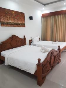 two beds in a hotel room with white sheets at Villa Pine Tree in Gili Trawangan