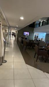 a lobby of a building with tables and chairs at Flat em Hotel de Luxo beira mar da grife Ritz suítes com vista ampla para todo o mar da cruz das almas, jatiúca e ponta verde, com toda estrutura de um hotel lindo e arrojado, academia, piscina e muito mais, venha viver essa experiência incrível! in Maceió