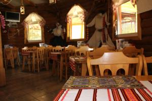 a restaurant with wooden tables and chairs and windows at Goryanyn in Pilipets