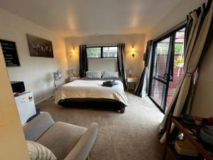 a bedroom with a bed and a couch and windows at Dinsdale oasis and private spa pool in Hamilton