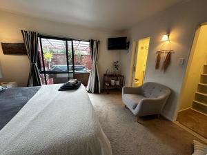 ein Schlafzimmer mit einem Bett, einem Stuhl und einem Fenster in der Unterkunft Dinsdale oasis and private spa pool in Hamilton