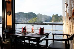 una mesa con sillas y copas de vino en el balcón en V'Spirit Cruise, en Ha Long