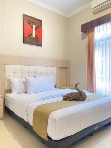 a bedroom with a large white bed with a large window at Ayuri Hotel Malioboro in Sentool