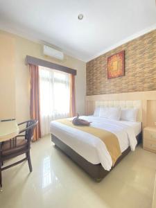 una camera con un grande letto e una scrivania di Ayuri Hotel Malioboro a Sentool