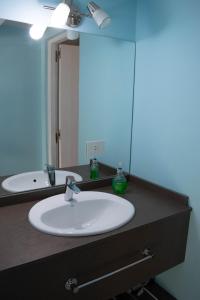 La salle de bains est pourvue d'un lavabo et d'un grand miroir. dans l'établissement Alfa & Omega, à Dina Huapi