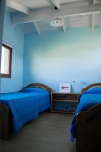 2 Betten in einem Zimmer mit blauen Wänden in der Unterkunft Alfa & Omega in Dina Huapi