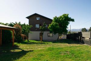 a house with a tree in the yard at Alfa & Omega in Dina Huapi
