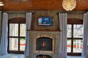 a living room with a stone fireplace with a tv at Villaggio di Roma in Campos do Jordão