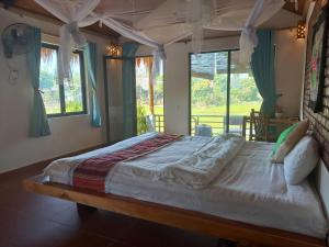 duże łóżko w pokoju z oknami w obiekcie Mai Chau Green house w mieście Mai Châu