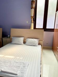 a bed with two pillows in a room with windows at Khách Sạn Như Ý in Ấp Tân Phú (1)