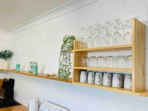 a kitchen with wooden shelves with glasses on it at Brooms Beach Stay in Brooms Head