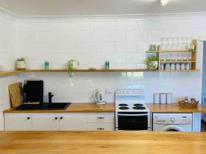 a kitchen with white cabinets and a stove top oven at Brooms Beach Stay in Brooms Head