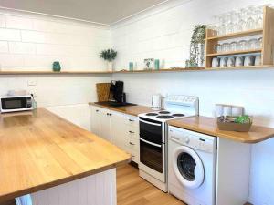 a kitchen with a stove and a washing machine at Brooms Beach Stay in Brooms Head