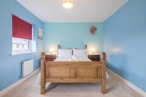 a bedroom with a bed with blue walls and two lamps at Modern and Comfy 3 bed Cambridge House in Cambridge