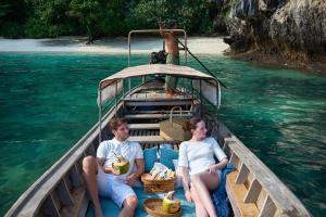 un homme et une femme assis sur un bateau dans l'eau dans l'établissement Cape Kudu Hotel, Koh Yao Noi, à Ko Yao Noi