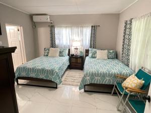 a bedroom with two beds and a chair at Elizabeth Retreat - Island time in Ocho Rios