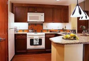 a kitchen with wooden cabinets and a white stove top oven at Marriott Ko olina beach club in Honokai Hale