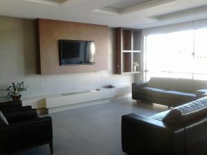 a living room with a couch and a tv on a wall at Hotel Areias Brancas in Rosário do Sul