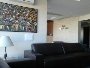 a living room with a couch and a painting on the wall at Hotel Areias Brancas in Rosário do Sul