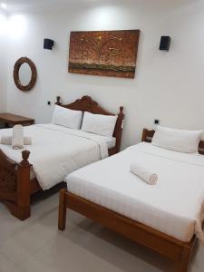 two beds in a room with white walls at Villa Pine Tree in Gili Trawangan