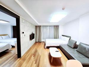 una camera d'albergo con due letti e un divano di Jeoung's House a Busan