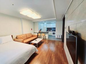 sypialnia z łóżkiem i kanapą oraz kuchnia w obiekcie Jeoung's House w Pusanie