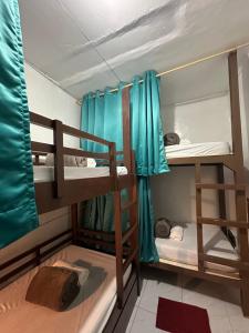a room with two bunk beds with blue curtains at Malapascua Budget Inn MBI DIVE CENTER in Malapascua Island