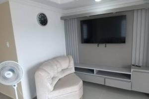 Il comprend un salon doté d'une chaise blanche et d'une télévision à écran plat. dans l'établissement Apartamento Amueblados Jireh, à San Onofre