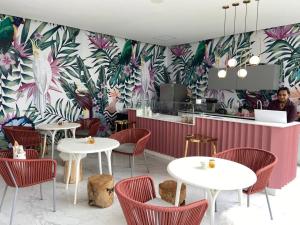 a restaurant with white tables and chairs and a floral wall at Increíble departamento en Bolongo punta de mita in Higuera Blanca