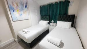 Duas camas num pequeno quarto com cortinas verdes em Garland Modern Close To Station 3 Bedroom City Apartment em Londres