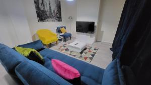 a living room with a blue couch and a yellow chair at Garland Modern Close To Station 3 Bedroom City Apartment in London