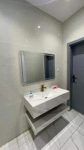 La salle de bains est pourvue d'un lavabo blanc et d'un miroir. dans l'établissement شقة غرفتين وصاله, à Al ‘Uqūl