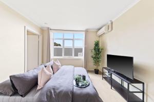 a bedroom with a large bed and a flat screen tv at A Comfy & Cozy Apt in Clifton Hill FREE Parking in Melbourne