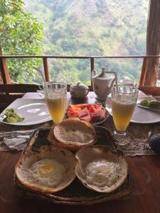 a plate of eggs and toast on a table with drinks at Mount Wood Star in Ella