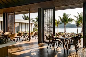 un ristorante con tavoli e sedie e vista sull'oceano di Anantara Quy Nhon Villas a Quy Nhon