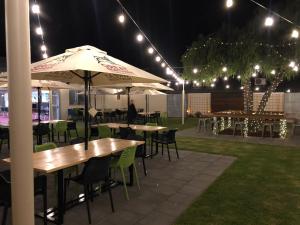 un patio con mesas, sillas y sombrillas por la noche en The Anglers Inn en Wallaroo