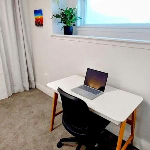 a laptop computer sitting on a white desk with a chair at City Fringe Apartment with garage in Wellington
