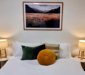 a bedroom with a white bed with a yellow pillow on it at City Fringe Apartment with garage in Wellington