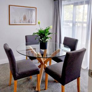 a dining room with a glass table and four chairs at City Fringe Apartment with garage in Wellington