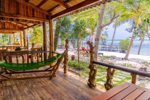 a hammock on a deck with a view of the beach at Dugong Resort Phu Quoc in Phu Quoc
