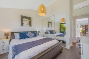 a bedroom with a large bed with blue pillows at Lighthouse Beach Luxury in Port Macquarie