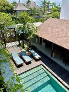 eine Terrasse mit Liegestühlen und einem Pool in der Unterkunft Luna Ola Villa Berawa in Canggu