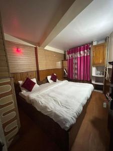 a bedroom with a large white bed with red pillows at Salix in Darjeeling