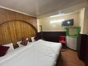 a bedroom with a large white bed with a wooden headboard at Salix in Darjeeling