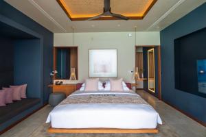 a bedroom with a large bed and a couch at Veligandu Maldives Resort Island in Rasdhoo